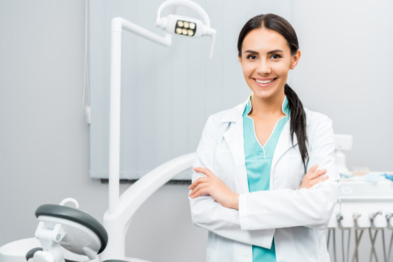 beautiful dentist standing with crossed arms in dental clinic